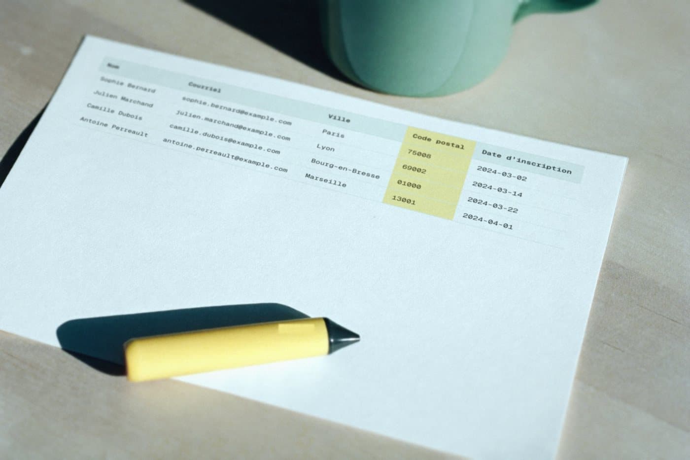 The cleaned file printed on a sheet, the postal code column highlighted in yellow, a highlighter resting on it.